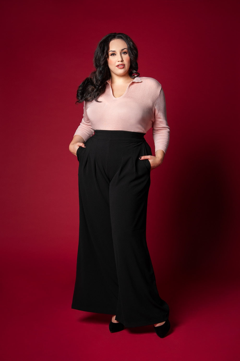 Pinup Girl Clothing model Coco Lamarr poses in PUG brand favorite Dietrich vintage inspired wide leg trouser palazzo pants with pockets made of high quality stretch crepe in black 30" inch inseam